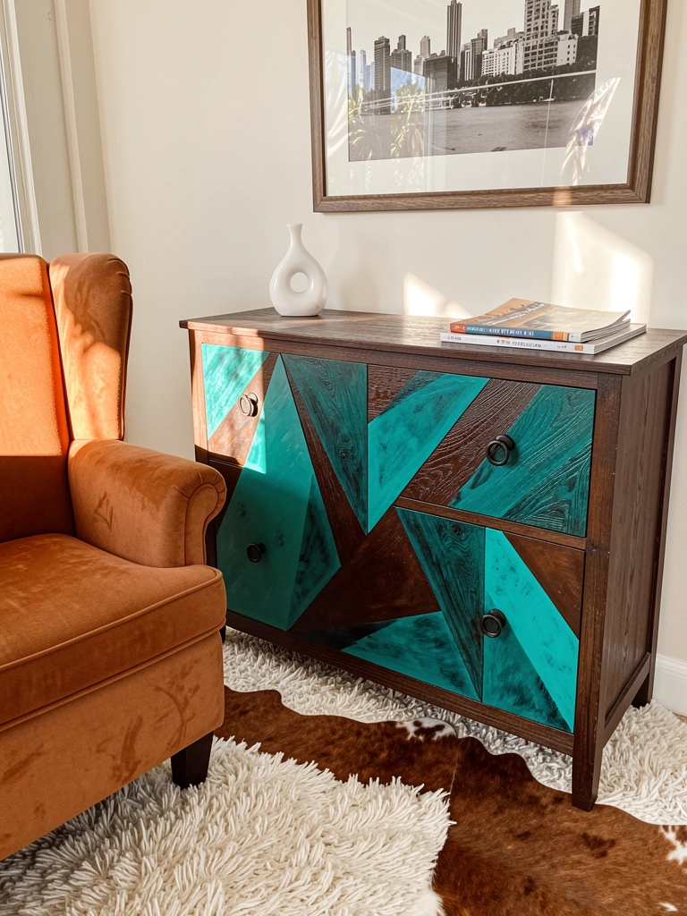 Cômoda de madeira escura com pintura geométrica em teal e turquesa, poltrona wingback caramelo e tapete bege felpudo, luz natural.