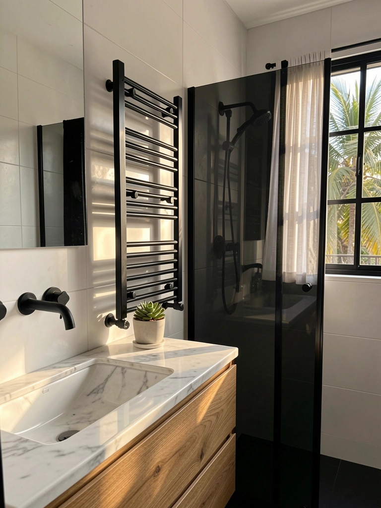 Mármore branco do tampo contrasta com o armário de madeira natural; toalheiro preto e ducha de vidro preto; vaso de suculenta sobre console de mármore.