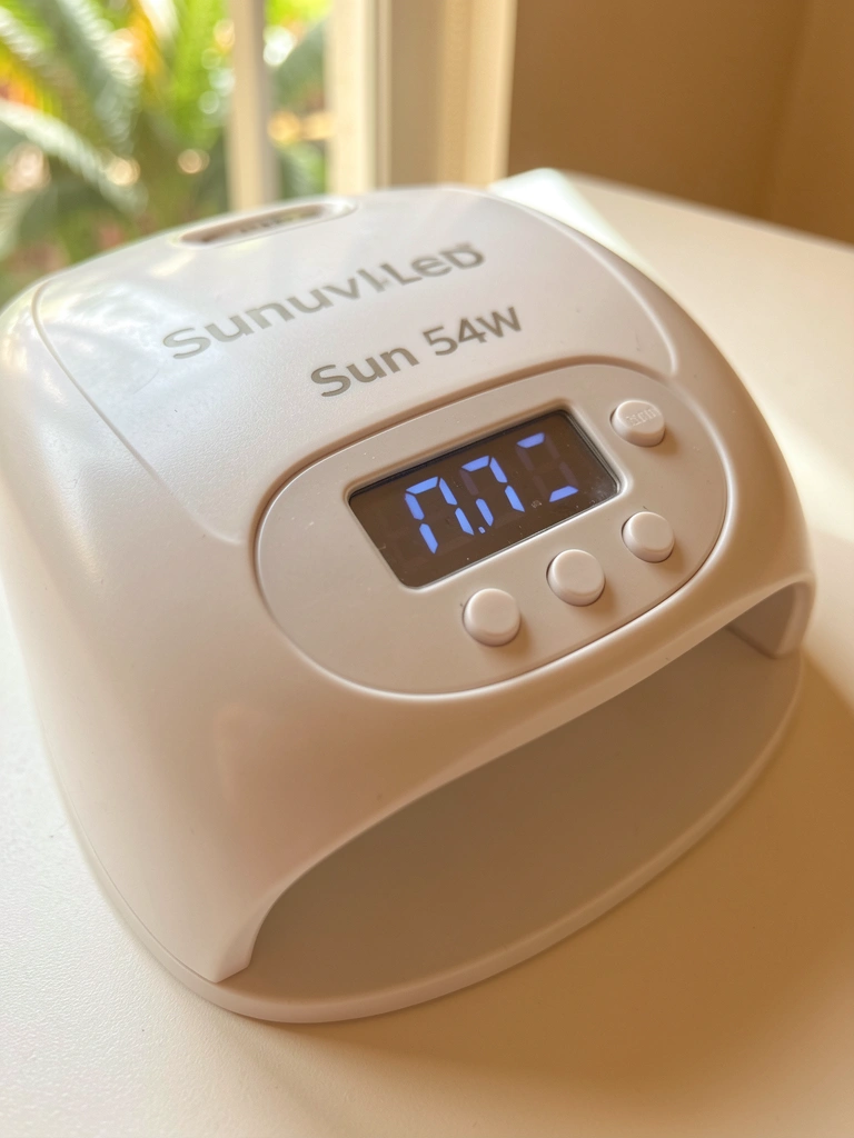 Luz difusa destaca o display digital e os botões da lâmpada Sunuvled 54W, com plástico texturizado e fundo branco desfocado.
