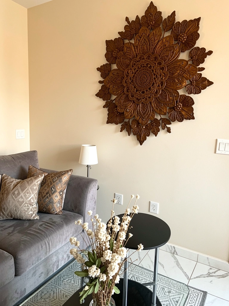 Mandala floral marrom em parede bege, sofá cinza com almofadas estampadas, mesa de centro preta e luminária branca.