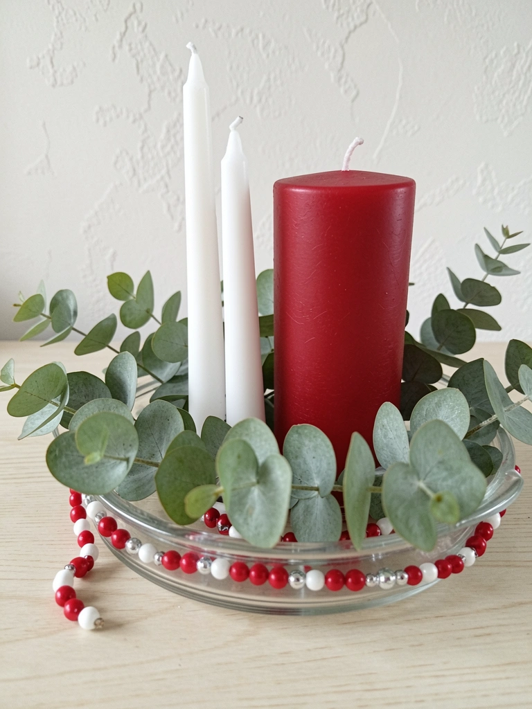 Mesa clara com galhos de eucalipto e velas simples dispostas sobre a superfície