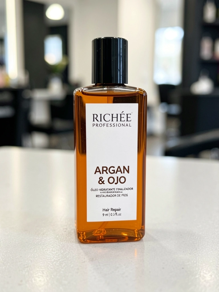 Frasco âmbar retangular com tampa preta e rótulo branco da Richée Professional sobre superfície cinza clara, com reflexos sutis de luz e fundo desfocado.